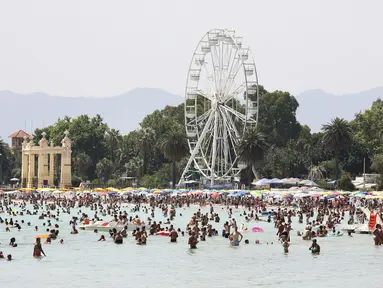 Orang-orang mencari kesegaran saat hari panas dengan suhu lebih dari 40 derajat Celcius di Pantai Mondello, Palermo, Sisilia, Italia, 16 Juli 2023. Suhu diperkirakan akan mencapai rekor tertinggi baru pada minggu ini. (Alberto Lo Bianco/LaPresse via AP)