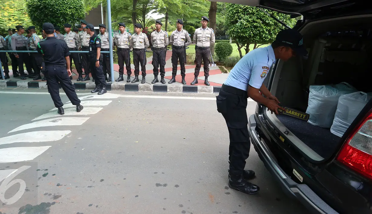 Pamdal DPR mengecek kendaraan sementara sejumlah aparat kepolisian berjaga di pintu masuk Gedung MPR/DPR RI,  Senayan, Jakarta, Jumat (31/3). Polda Metro Jaya memberikan pengamanan ketat di sekitar DPR terkait aksi 31 Maret. (Liputan6.com/Johan Tallo)