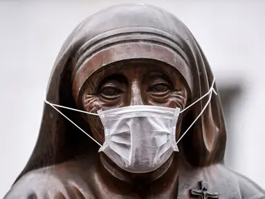 Masker terpasang pada wajah patung Bunda Teresa di Pristina, Kosovo, Kamis (19/12/2019). Pristina dan beberapa kota di Kosovo mengalami polusi udara tingkat tinggi. (Armend NIMANI/AFP)