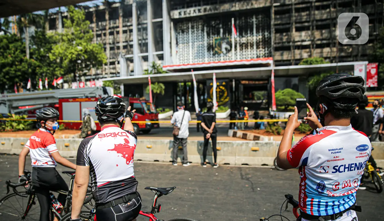 Sejumlah pesepeda mengambil gambar gedung utama Kejaksaan Agung RI yang terbakar di Jalan Sultan Hasanuddin, Jakarta Selatan, Minggu (23/8/2020).  Banyak warga yang memadati Jalan Hasanuddin untuk melihat langsung kondisi gedung Kejaksaan Agung yang hangus dilalap api. (Liputan6.com/Faizal Fanani)