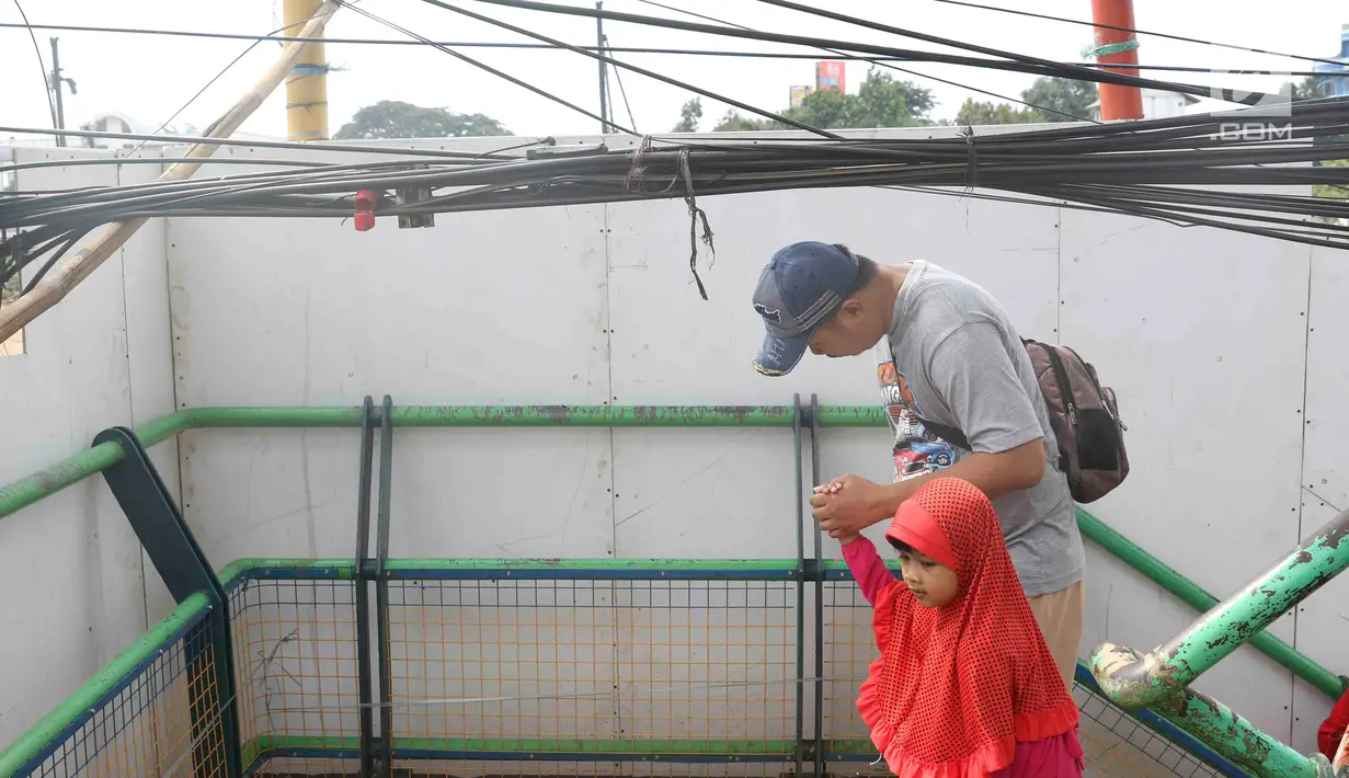 Pejalan kaki melintasi jembatan penyeberangan orang yang terhalang instalasi kabel di Depok, Jawa Barat, Sabtu (8/12). Selain mengganggu kenyamanan, keberadaan instalasi kabel semrawut tersebut membahayakan pejalan kaki. (Liputan6.com/Immanuel Antonius)