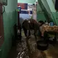 Warga bersih-bersih rumah usai terendam banjir di kawasan Kampung Melayu, Jakarta, Senin (8/11/2021). Banjir akibat luapan Kali Ciliwung tersebut merendam pemukiman setinggi 60 cm sejak 7 November 2021 sore. (Liputan6.com/Faizal Fanani)