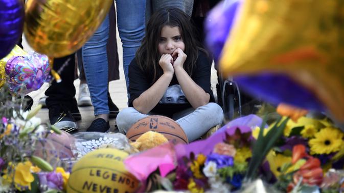 Seorang anak saat menghadiri acara penghormatan untuk Kobe Bryant dan putrinya Gianna di luar Staples Center, Los Angeles, California (28/1/2020). Kobe Bryant meninggal bersama putrinya Gianna dalam kecelakaan helikopter di Calabasas, California. (Kevork Djansezian/Getty Images/AFP)