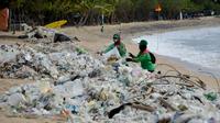 Pekerja mengumpulkan sampah plastik saat membersihkan pantai Kuta dekat Denpasar di pulau wisata Bali (6/1/2021). Pada 1 Januari 2021, sekira 30 ton sampah diangkut dari kawasan Pantai Kuta dalam kegiatan bersih-bersih pantai. (AFP/Sonny Tumbelaka)