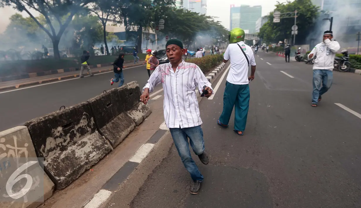 Massa berlari saat polisi menembakkan gas air mata di depan gedung KPK, Jakarta, Jumat (20/5). Aksi menuntut KPK untuk segera mengusut keterlibatan Ahok di RS Sumber Waras ini berakhir ricuh. (Liputan6.com/Yoppy Renato)