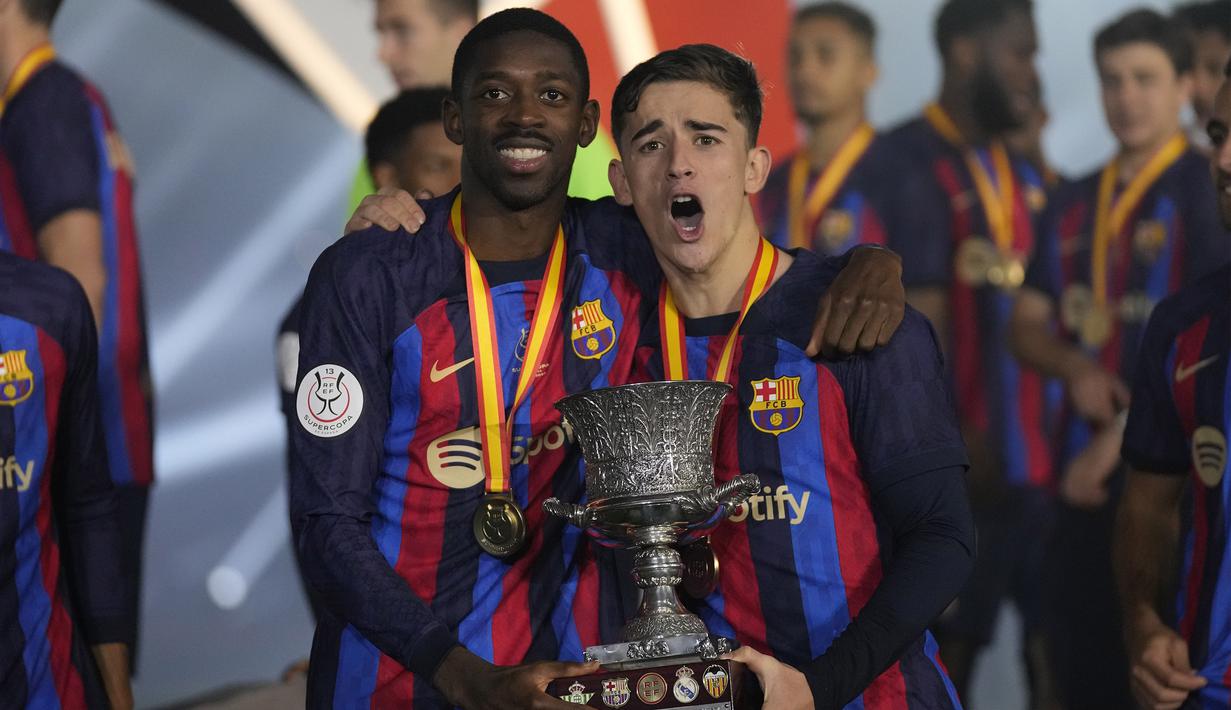 Pemain Barcelona, Ousmane Dembele (kiri) dan Gavi berpose bersama trofi Supercopa de Espana 2023 setelah keluar sebagai juara dalam pertandingan Supercopa de Espana melawan Real Madrid di King Fahd Stadium, Arab Saudi, Senin (16/1/2023) WIB. (AP Photo/Hussein Malla)