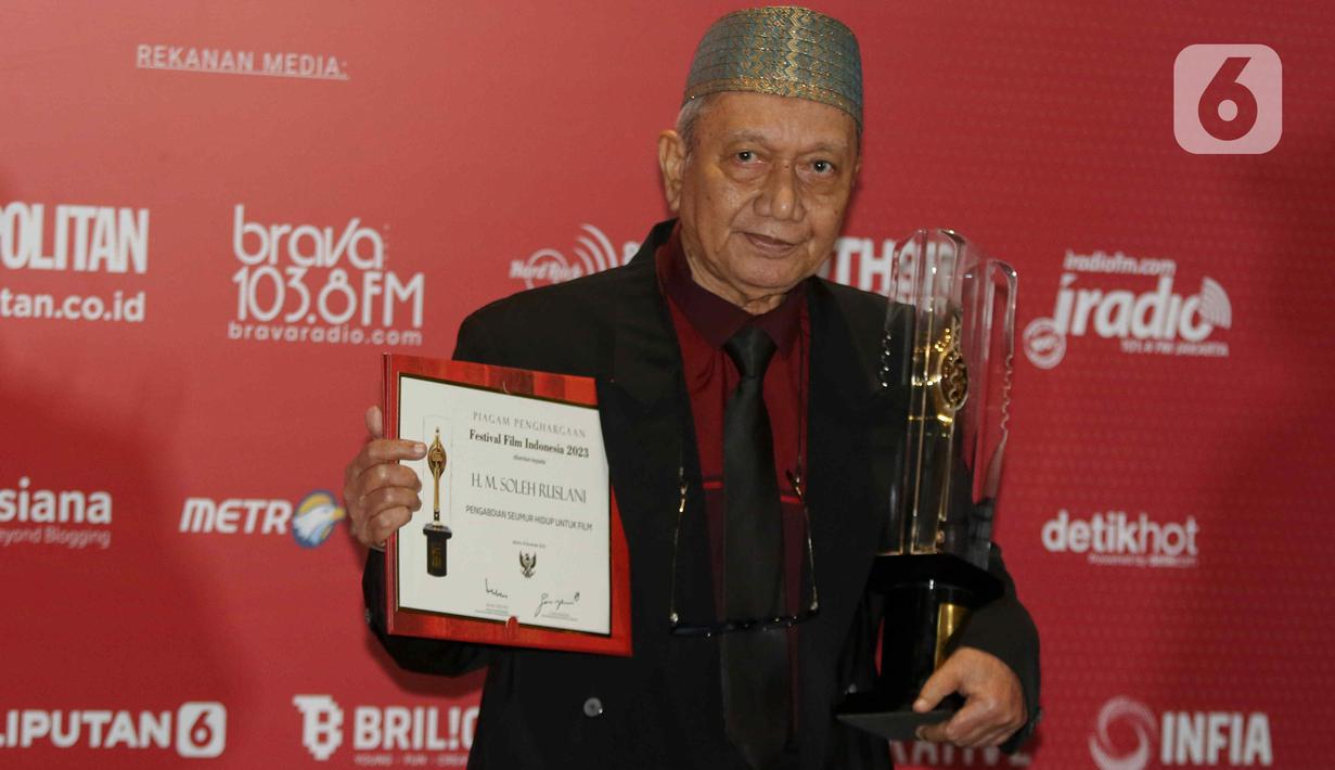 Sinematografer H.M. Soleh Ruslani berpose memegang piala saat menerima Anugerah Festival Film Indonesia (FFI) 2023 kategori  Pengabdian Seumur Hidup di Ciputra Artpreneur, Jakarta, Selasa (14/11/2023). (Liputan6.com/Herman Zakharia)