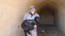 Seorang staf menggendong kambing di peternakan milik koperasi pembiakan kambing hitam di Desa Wangwan, wilayah Zhenyuan, Provinsi Gansu, China, 21 Januari 2021. Wilayah Zhenyuan mengubah gua tempat tinggal yang ditelantarkan menjadi kandang kambing dalam beberapa tahun terakhir. (Xinhua/Ma Sha)