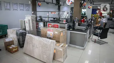Petugas ekspedisi melayani pengiriman paket pelanggan (kanan) di Kantor Cabang JNE, Jakarta, Kamis (30/12/2021). Supply Chain Indonesia (SCI) memprediksi peningkatan pengiriman barang pada akhir tahun ini mencapai 20 persen untuk ke wilayah luar Pulau Jawa dan Bali. (Liputan6.com/Faizal Fanani)