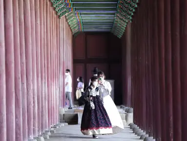 Seorang wanita mengenakan masker sebagai tindakan pencegahan terhadap virus corona mengambil foto temannya saat mereka mengunjungi Istana Gyeongbok untuk merayakan liburan Chuseok, Hari Thanksgiving versi Korea, di Seoul, Korea Selatan, Rabu (22/9/2021). ( AP Photo/Ahn Young-joon)