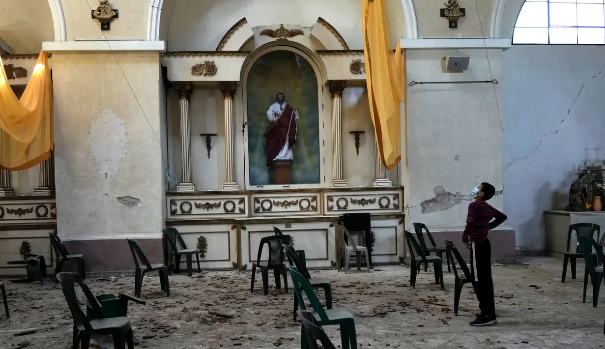 Seorang anak laki-laki berdiri di gereja San Juan Bautista yang sebagian runtuh, dipicu berkekuatan 6,2 skala Richter semalam di Amatitlan, Guatemala, 16 Februari 2022. Gempa bumi menyebabkan kerusakan yang mempengaruhi hampir 25.000 orang. (AP Photo/Moises Castillo)