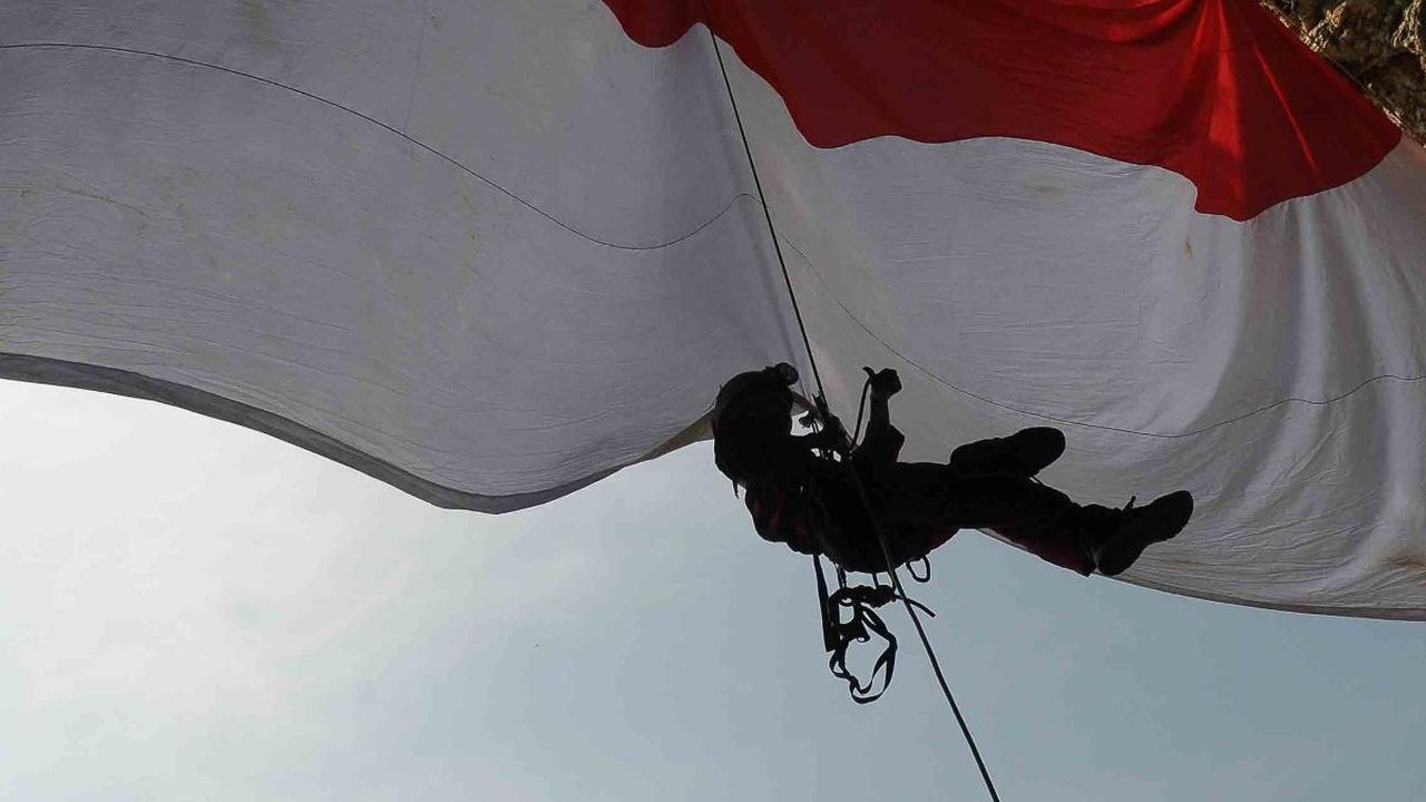 Bendera merah putih yang berukuran besar 6 x 4 meter itu dibentangkan pada mulut goa.