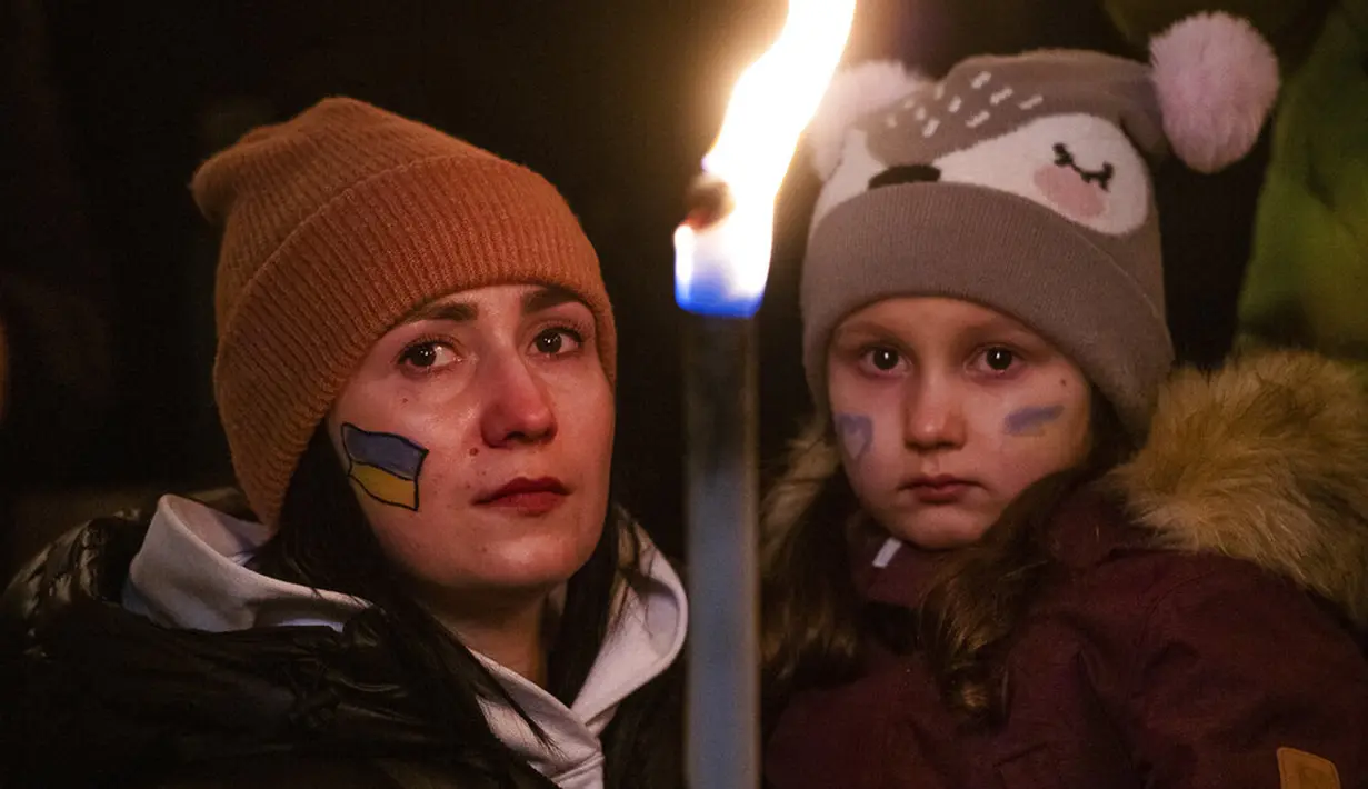 Seorang wanita dan seorang anak memegang obor saat demonstrasi untuk Ukraina yang diselenggarakan oleh Greenpeace di Heroes Square, Budapest, Hungaria, 9 Maret 2022. Lebih dari 1,5 juta orang telah menyeberang dari Ukraina ke negara-negara tetangga. (AP Photo/Anna Szilagyi)
