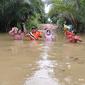 Kades Kinipan Wilem Hengky (baju oranye) saat melintasi banjir yang melanda Desa Kinipan beberapa waktu lalu. (foto: dokumentasi pribadi)