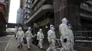 Petugas kebersihan yang mengenakan pakaian pelindung berkumpul di daerah Yau Ma Tei, di Hong Kong, Sabtu (23/1/2021). Penguncian akan berlangsung sampai semua orang di area yang ditentukan telah diuji. (AP Photo/Vincent Yu)