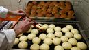 Seorang pekerja menyiapkan berliner (donat Jerman) yang akan dijual dengan jarum suntik penuh raspberry jelly di toko roti Kreyenbuhl di Muri, Swiss, 5 Februari 2021. Pembeli dapat menyuntikkan sendiri "vaksin" ke dalam donut dengan pilihan rasa raspberry atau Bailey-liqueur. (STEFAN WERMUTH/AFP)
