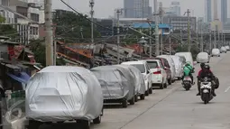 Pengendara motor melintas di jalur inspeksi Kanal Banjir Barat, Jakarta, Senin (6/3). Keterbatasan lahan menyebabkan sejumlah kendaraan parkir di tempat tersebut, meskipun telah terpampang larangan parkir. (Liputan6.com/Immanuel Antonius)
