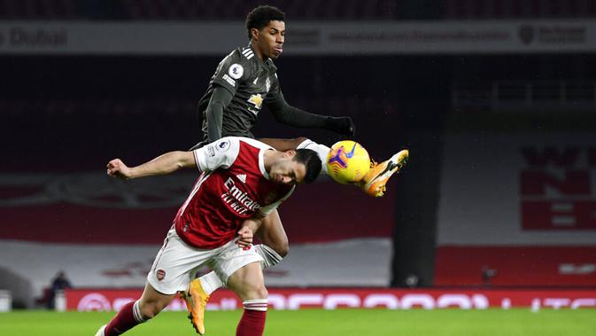 Penyerang Manchester United, Marcus Rashford, berebut bola dengan pemain Arsenal, Cedric Soares, pada laga Liga Inggris di Stadion Emirates, Sabtu (30/1/2021). Kedua tim bermain imbang 0-0. (Shaun Botterill/Pool via AP)