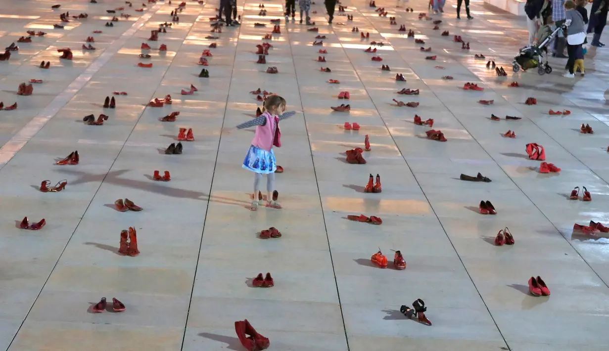 Seorang anak di antara instalasi ratusan sepatu merah untuk memprotes kekerasan terhadap perempuan di kota pesisir Tel Aviv,Selasa (4/12). Sepanjang tahun ini, 24 perempuan Israel tewas akibat tindakan kekerasan dalam rumah tangga. (JACK GUEZ/AFP)