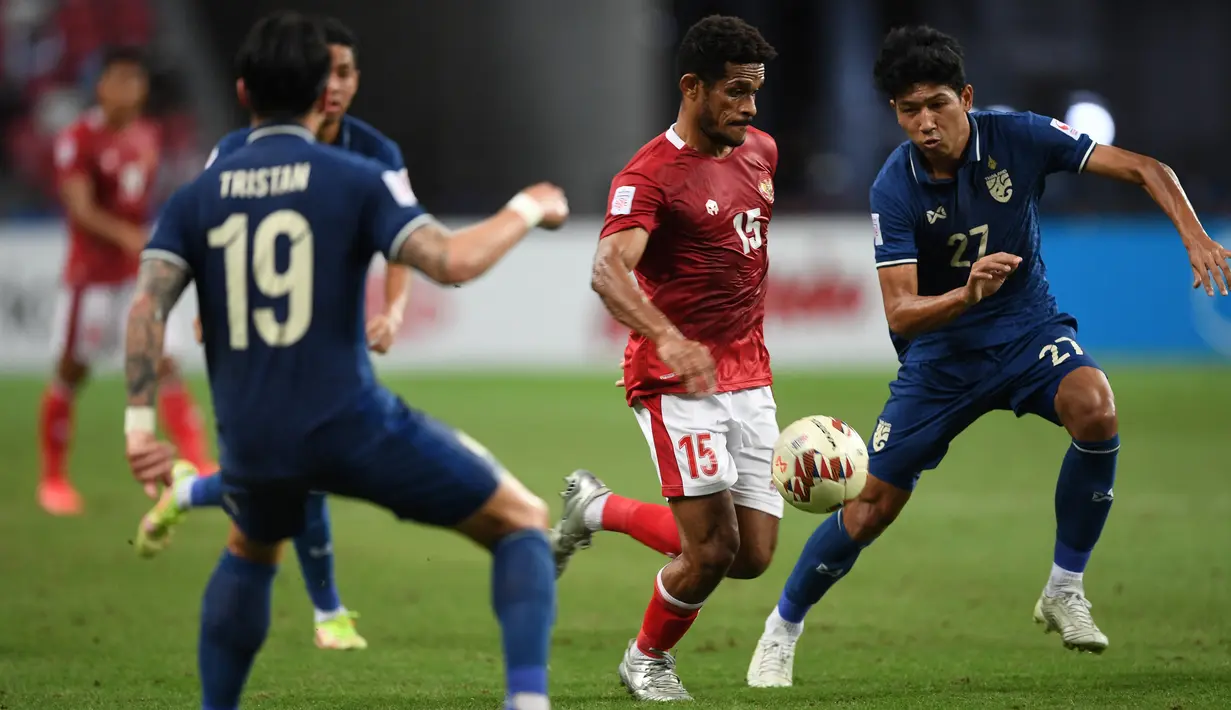 Gelandang Timnas Indonesia Ricky Richardo Kambuaya mengontrol bola dibayangi pemain Timnas Thailand Tristan Do dan Weerathep Pomphun dalam pertandingan Babak Final Leg 1 Piala AFF 2020 di National Stadium, Singapura, Rabu (29/12/2021). Skuat Garuda menyerah 0-4 dari Thailand (Roslan RAHMAN/AFP)