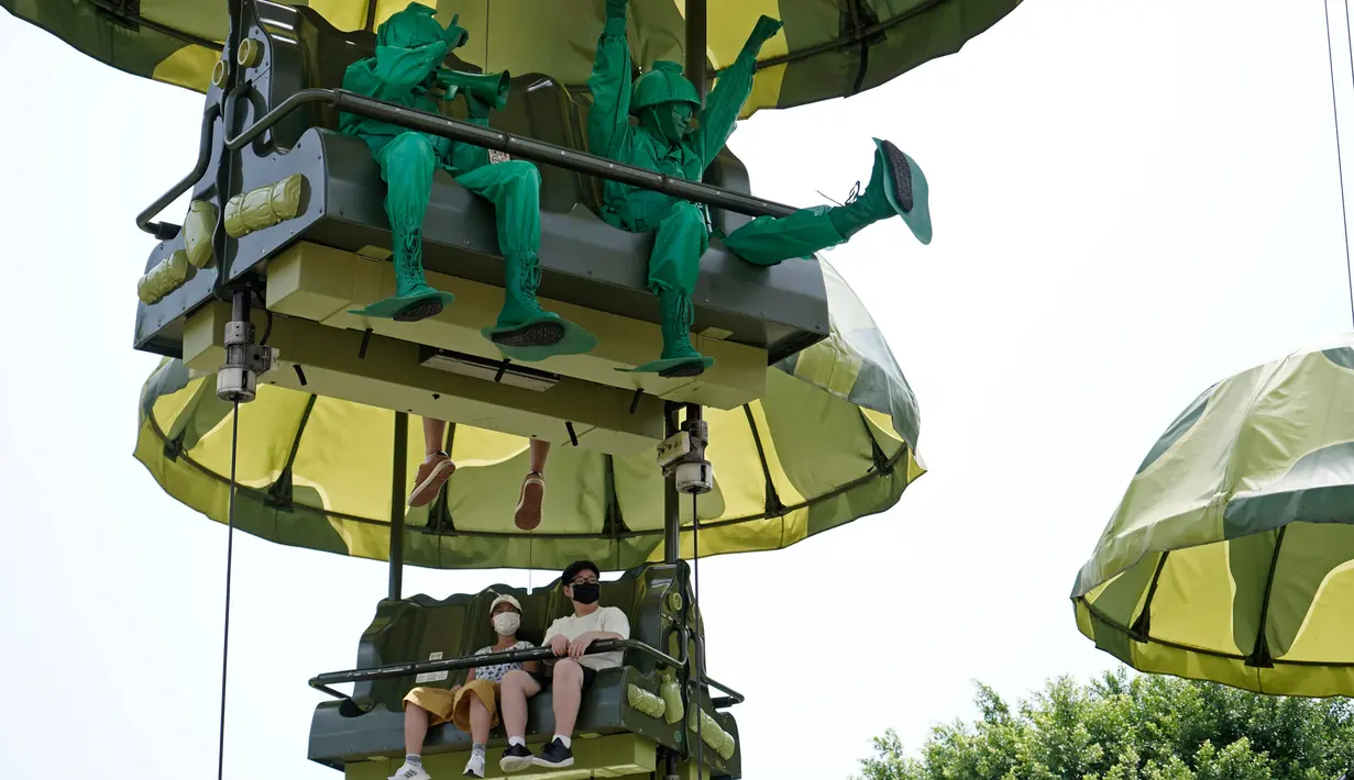 Pengunjung yang mengenakan masker menaiki wahana Toy Soldier Parachute Drop di Disneyland Hong Kong pada Jumat (25/9/2020). Setelah dibuka dan tutup kembali, Disneyland Hong Kong dibuka kembali untuk wisatawan. (AP Photo/Kin Cheung)