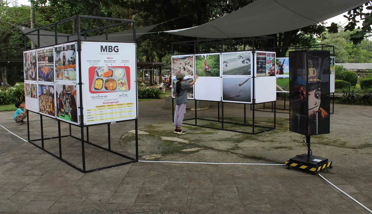 Bertajuk Haluan Merah Putih, pameran karya jurnalistik sebagai upaya menghadirkan informasi publik di ruang terbuka, kegiatan ini terbuka untuk umum dan berlangsung hingga 1 Januari 2026. Tampak dalam foto, pengunjung menyaksikan karya foto jurnalistik dalam pameran Haluan Merah Putih Roadshow yang digelar di Selasar Kantin Taman Margasatwa Ragunan, Jakarta Selatan, Rabu (24/12/2025). (merdeka.com/magang/Rendi Saputra)