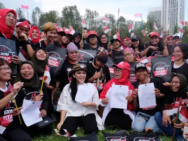 Ketua Nasional Relawan Tim Alpha Jokowi-Ma'ruf Amin, Rieke Diah Pitaloka (tengah) bersama pekerja migran menunjukkan surat deklarasi Tim Zona Alpha Hongkong mendukung pasangan Jokowi-Ma'aruf Amin di Hongkong, Minggu (23/9). (Liputan6.com/HO/Tim Alpha)