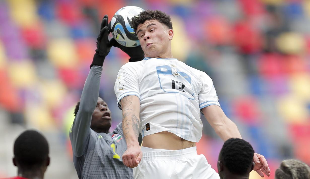 Pemain Uruguay U-20, Alan Matturro (kanan) berusaha menanduk bola dihalangi kiper Gambia U-20, Pa Ebou Dampha pada laga 16 besar Piala Dunia U-20 di Estadio Unico Madre de Ciudades, Argentina, Jumat (02/06/2023) dini hari WIB. (AP Photo/Nicolas Aguilera)