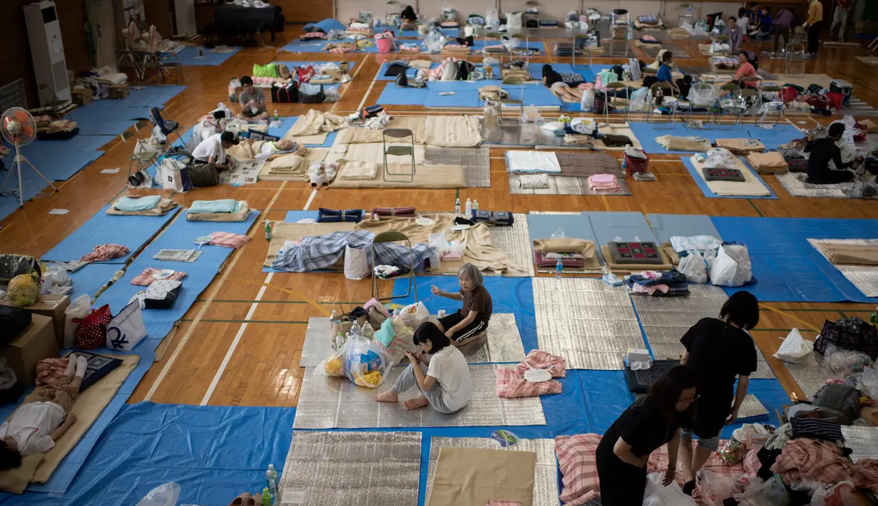Para pengungsi beristirahat di lokasi pengungsian di Mabi, Prefektur Okayama, Jepang, Rabu (11/7). Pemerintah Jepang menyatakan banjir disertai tanah longsor telah menewaskan 179 orang. (Martin BUREAU/AFP)