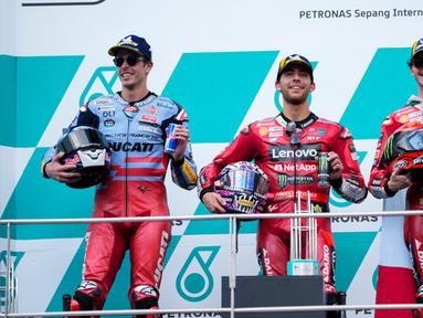 Pemenang pembalap Italia Enea Bastianini (tengah), pembalap Spanyol peringkat kedua Alex Marquez (kiri), dan pembalap Italia peringkat ketiga Francesco Bagnaia berpose untuk fotografer di podium balapan MotoGP Malaysia 2023 di Sepang, Malaysia Minggu (12/11/2023). (AP Photo/Vincent Thian)