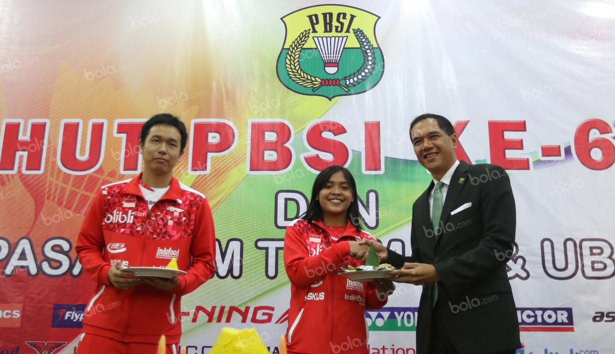 Ketua Umum PBSI, Gita Wirjawan (kanan), menyerahkan potongan tumpeng kepada Hendra Setiawan (kiri) dan Gregoria Mariska dalam perayaan HUT PBSI ke-65 di Pelatnas Bulutangkis PBSI, Cipayung, Jakarta, (9/5/2016). (Bola.com/Arief Bagus)