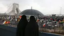 Dua wanita memakai payung saat menghadiri upacara peringatan 40 tahun Revolusi Islam Iran di Menara Kebebasan, Teheran, Senin (11/2). Sebagian besar masyarakat Iran mengucap syukur atas 40 tahun revolusi. (AP Photo/Vahid Salemi)