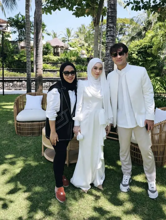 Lesti Kejora mengenakan kerudung pashmina warna putih polos senada dengan long dress lengan panjangnya. Dress pun memiliki aksen pita, ia pun hadir bersama suaminya, Rizky Billar yang tampil serba putih. [@rikawirtjes]