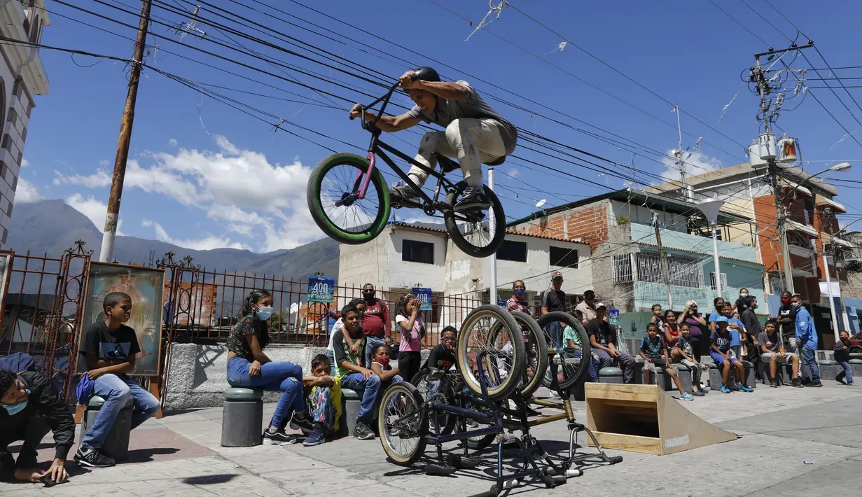 Pebalap BMX Leudar Ruiz melakukan aksi dalam sebuah pertunjukan yang menandai peringatan 400 tahun permukiman kumuh Petare di Caracas, Venezuela (17/2/2021). Petare yang merupakan kawasan kumuh terbesar di Venezuela menjadi rumah bagi lebih dari 500.000 jiwa. (AP Photo/Ariana Cubillos)