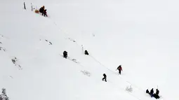 Petugas mengevakuasi korban helikopter yang jatuh di kawasan ski Campo Felice, Italia, Selasa (24/1). Berdasarkan laporan awal helikopter tersebut jatuh usai menjemput seseorang yang terluka akibat kecelakaan ski. (AP Photo)