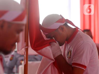 Warga binaan narapidana terorisme (napiter) mencium bendera Merah Outih saat melakukan ikrar dan janji setia Negara Kesatuan Republik Indonesia (NKRI) di Lapas Narkotika Kelas IIA, Gunung Sindur, Bogor, Jawa Barat, Kamis (1/6/2023). Sebanyak 76 warga binaan kasus terorisme melakukan ikrar dan janji setia NKRI sebagai salah satu wujud keberhasilan pembinaan dan mendorong kesadaran mereka untuk kembali dan mengakui Tanah Air Indonesia. (merdeka.com/Arie Basuki)