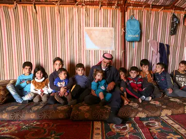 Abderrazaq Khatoun, beristirahat dengan 11 cucunya yang yatim piatu di dalam tenda di desa Harbanoush, di Idlib, Suriah pada 11 Maret 2021. Perang Suriah yang merampas 13 anak Khatoun dan salah satu istrinya, membuat kakek 83 tahun itu membesarkan 11 cucu yatim piatu sendirian. (Ahmad al-ATRASH/AFP)