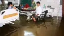 Pasien dan anggota keluarganya berada di dalam bangsal yang tergenang banjir di Nalanda Medical College Hospital, daerah Bihar, India, 29 Juli 2018. Rumah sakit itu digenangi air kotor dengan sejumlah ikan terlihat berenang memenuhi lantai. (AFP PHOTO)