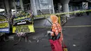 Pejalan kaki melintas dekat karangan bunga di dekat lokasi ledakan bom, Terminal Kampung Melayu, Jakarta, Kamis (25/5). Karangan bunga itu tanda duka cita pihak kepolisian terhadap tiga polisi yang gugur dan para korban luka. (Liputan6.com/Faizal Fanani)