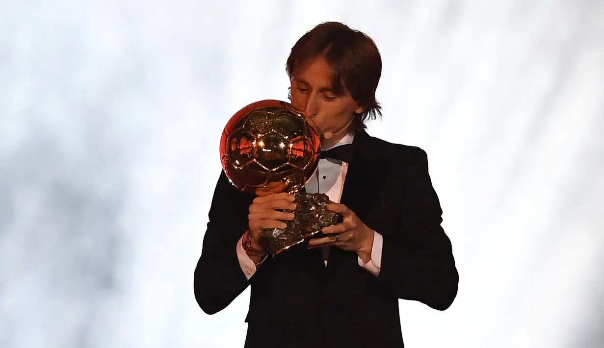 Gelandang Real Madrid, Luka Modric mencium trofi setelah memenangkan penghargaan Ballon d'Or 2018 pada malam penganugerahan di Paris, Senin (3/12). Penghargaan individu ini menjadi gelar Ballon d'Or pertama sepanjang karier Modric. (FRANCK FIFE/AFP)