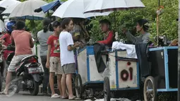 Sejumlah warga menunggu pakaiannya yang sedang dikecilkan oleh penjahit keliling di kawasan Lenteng Agung, Jakarta, Senin (4/7). Menjelang hari raya Idul Fitri, penjahit 'vermak levis' keliling mulai kebanjiran rezeki. (Liputan6.com/Yoppy Renato)