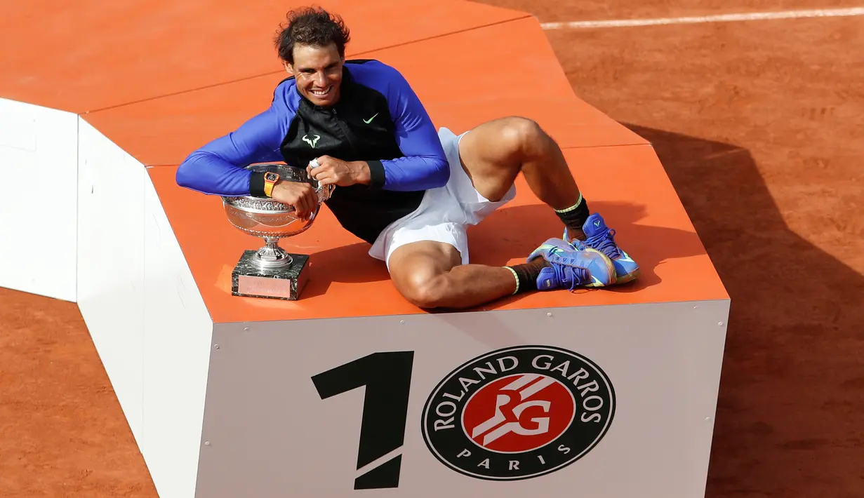 Petenis Rafael Nadal berpose dengan trofinya usai mengalahkan Stan Wawrinka pada final Prancis Terbuka di Roland Garros, Minggu (11/6). Atas kemenangan ini, Nadal sukses meraih gelar La Decima alias ke-10 di Prancis Open 2017. (AP Photo/Petr David Josek)