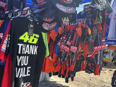 Perhelatan akbar ajang MotoGP Mandalika 2023 sebagai penyelenggaraan yang kedua kali tentunya menarik minat para pecinta balap di tanah air. Sehari menjelang balapan utama, Sabtu (14/10/2023) suasana di sekitar Sirkuit Mandalika sebagai venue balapan sudah mulai ramai dikunjungi para penonton. Hal ini ternyata dimanfaatkan beberapa orang untuk mengais rejeki dengan menggelar dagangan berupa makanan hingga aksesoris balap. Seperti yang dilakukan seorang pedagang aksesoris balap asal Bandung, Yogi, bersama dua rekannya yang rela menempuh jarak ribuan kilometer melintasi darat dan lautan untuk menjajakan dagangannya di sekitar Sirkuit Mandalika. (Bola.com/Benediktus Gerendo Pradigdo)