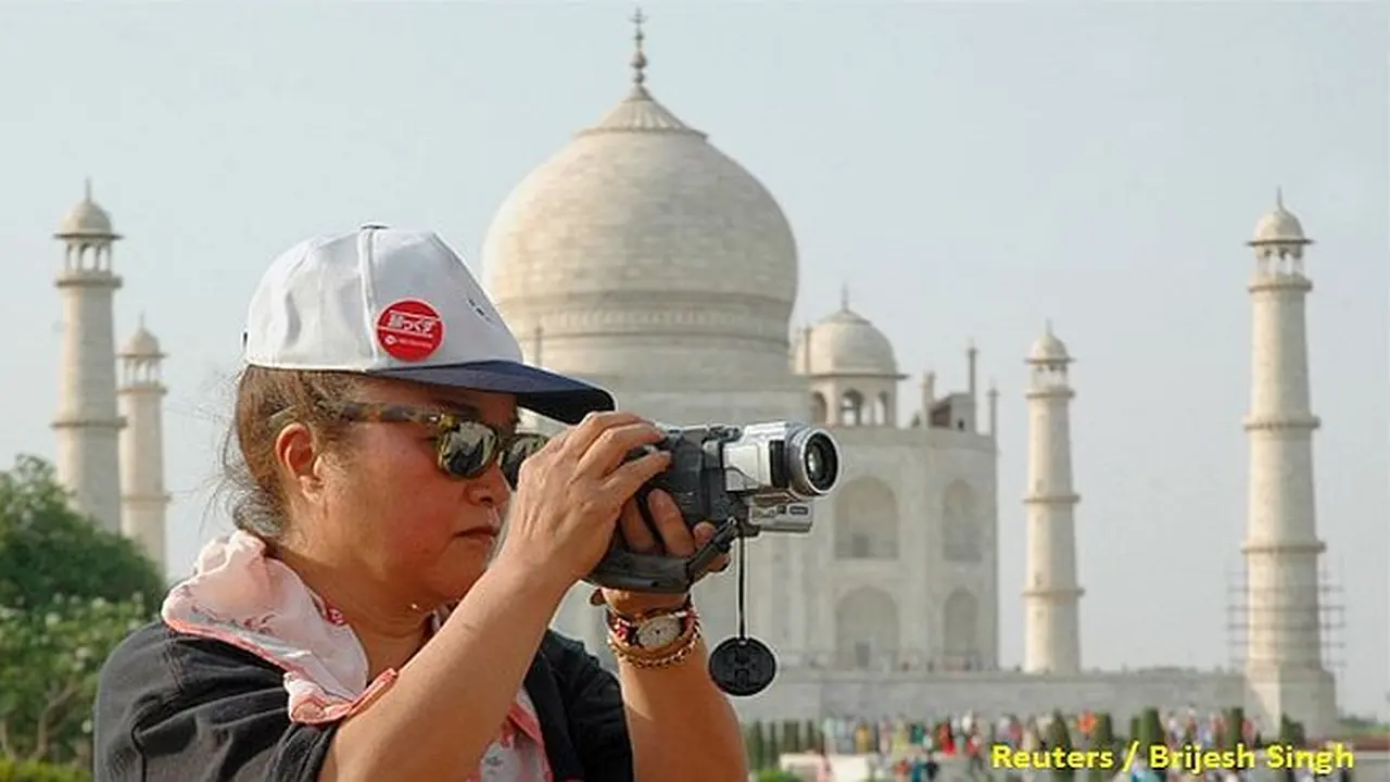 Seorang turis sedang mengambil foto di depan Taj Mahal