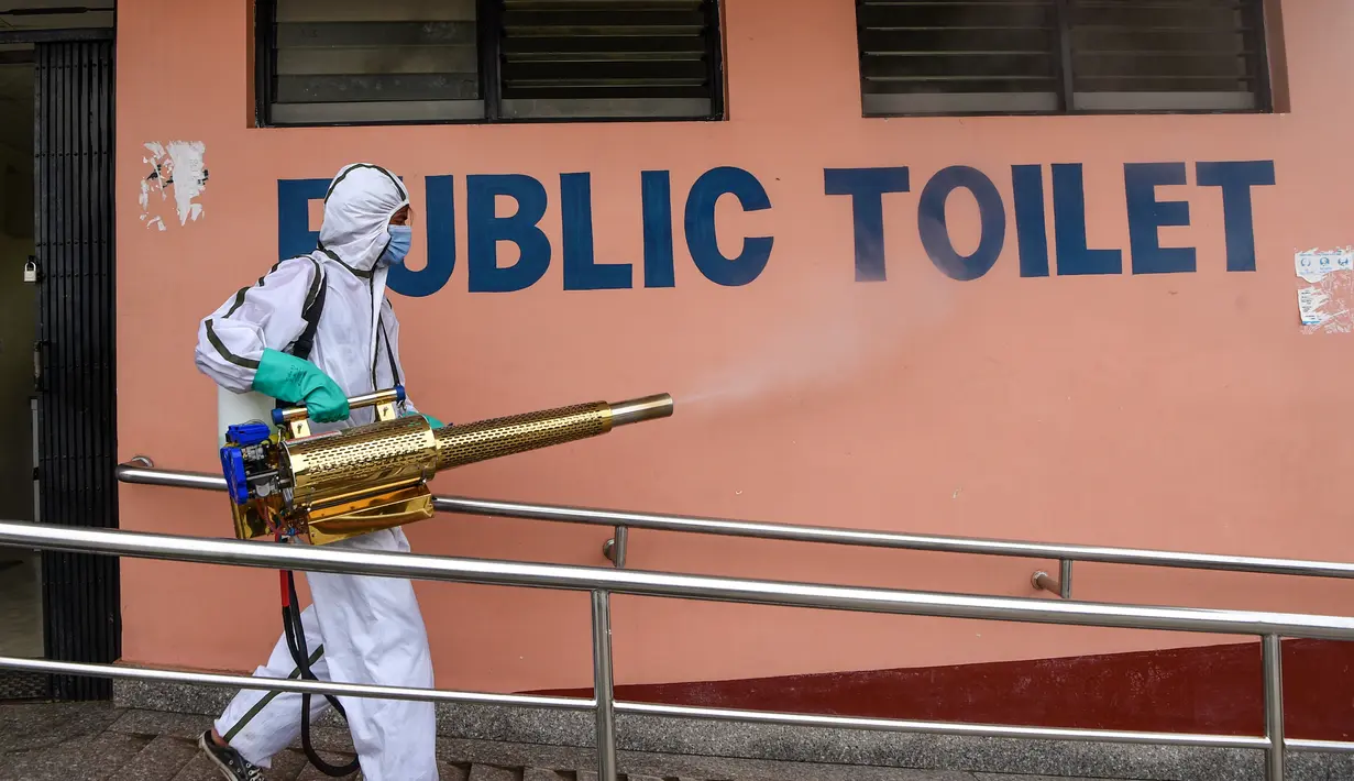 Pekerja yang mengenakan Alat Pelindung Diri (APD) menyemprotkan disinfektan toilet umum di terminal bus di Kathmandu, Kamis (17/9/2020). Pemerintah Nepal melonggarkan pembatasan yang diberlakukan sebagai tindakan pencegahan virus corona pada transportasi umum jarak jauh. (PRAKASH MATHEMA/AFP)