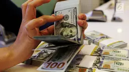 Petugas bank menghitung uang dollar AS di Jakarta, Jumat (20/10). Nilai tukar Rupiah terhadap Dolar Amerika Serikat (USD) masih belum beranjak dari level Rp 13.500-an per USD. (Liputan6.com/Angga Yuniar)