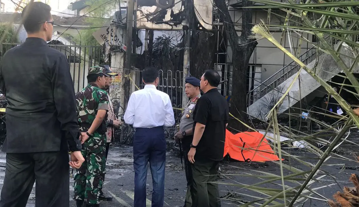 Presiden Joko Widodo (Jokowi) mendengarkan penjelasan Kapolri Jenderal Tito Karnavian terkait situasi dan kondisi saat meninjau Gereja Kristen Indonesia yang menjadi lokasi ledakan bom di Jalan Arjuna, Surabaya, Minggu (13/5). (Liputan6.com/Istimewa)