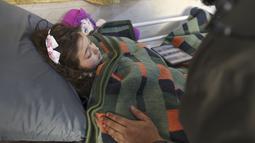 Gadis Suriah Sham Sheikh Mohammad (9) yang diselamatkan setelah empat puluh jam di bawah reruntuhan gempa Turki-Suriah yang mematikan, terbaring di ranjang rumah sakit di provinsi Idlib yang dikuasai pemberontak, pada 17 Februari 2023. Little Sham, seperti banyak orang yang selamat dari gempa berkekuatan M 7,8 yang menewaskan lebih dari 44.000 orang di seluruh Turki dan Suriah pada 6 Februari, sekarang menderita apa yang oleh dokter disebut crush syndrome. (Omar HAJ KADOUR / AFP)