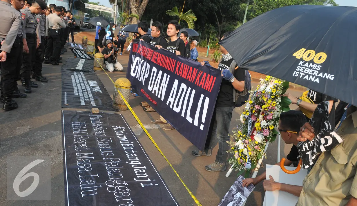 Spanduk berisi tuntutan penuntasan kasus pelanggaran HAM digelar di depan Istana Negara, Jakarta, Kamis (2/7/15). Dalam aksinya mereka meminta kepada Jokowi untuk menuntaskan kasus pembunuhan Jopi. (Liputan6.com/Herman Zakharia)