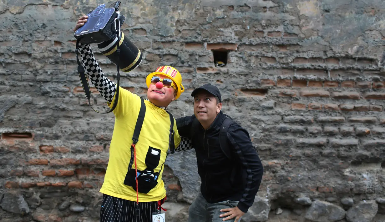 Seorang pejalan kaki berswafoto dengan badut saat acara Hari Badut Nasional di ibu kota Peru, Lima, Kamis(25/5). Tanggal 25 Mei merupakan peringatan Hari Badut Nasional bagi warga Peru. (AP Photo/Martin Mejia)
